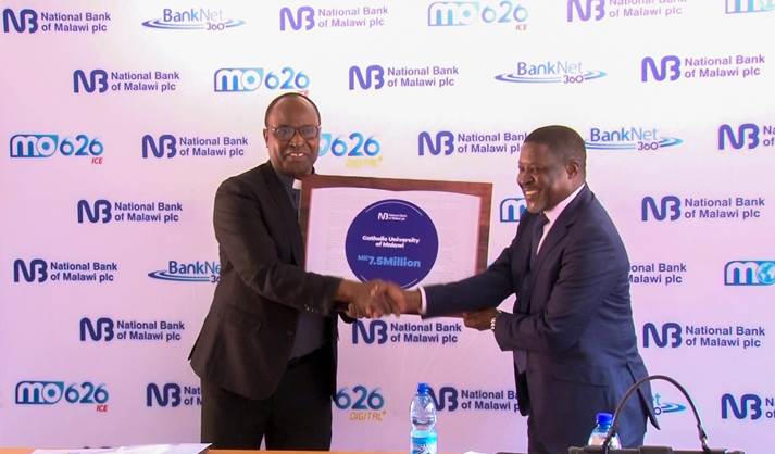 Rev. Fr. Dr George Buleya (L) receiving the dummy cheque from the, Head of Corporate Banking, William Chatsala