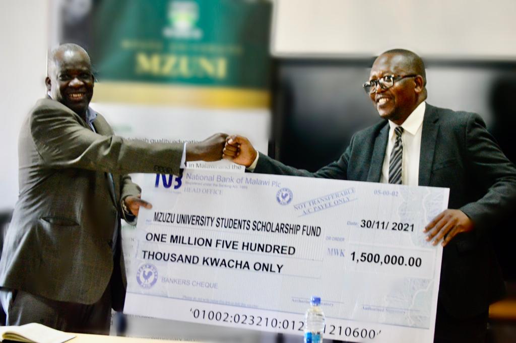 Mzungu (right) presents the dummy cheque to Professor Saka